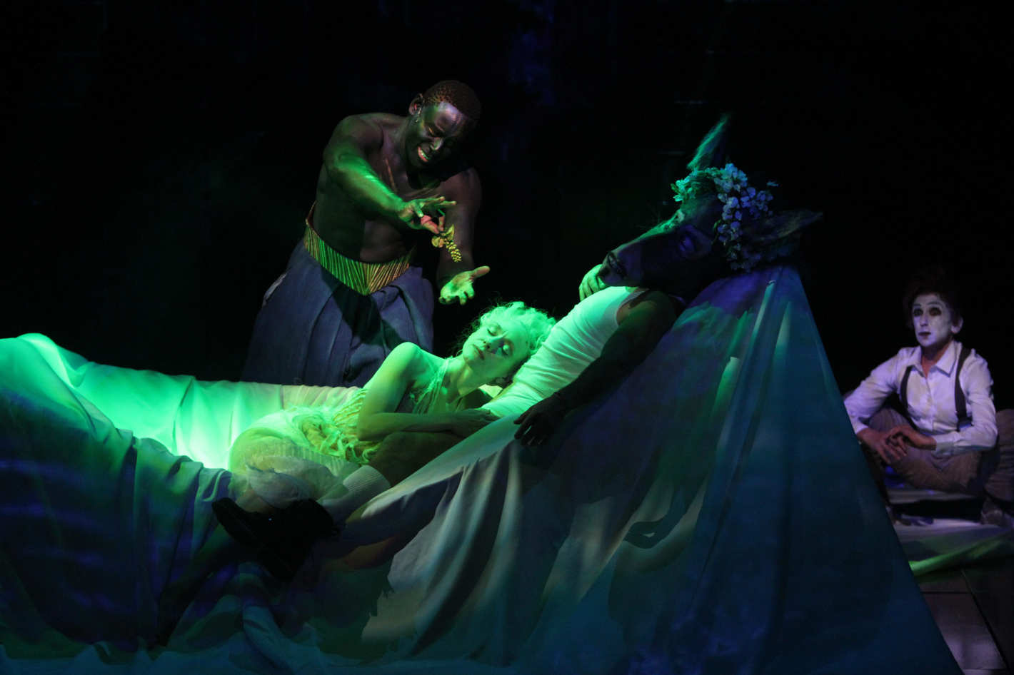 King Oberon (David Harewood) comes across his wife Titania (Tina Benko) curled in the arms of the actor Bottom (Max Casella) who was been transformed into a donkey, while the knave Puck (Kathryn Hunter) looks on in A Midsummer Night's Dream (2014)