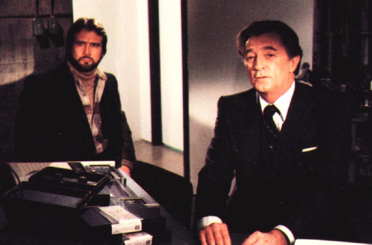 (l to r) Lee Majors as the advertising agency creative director who uncovers a conspiracy and the agency's director Robert Mitchum in Agency (1979)