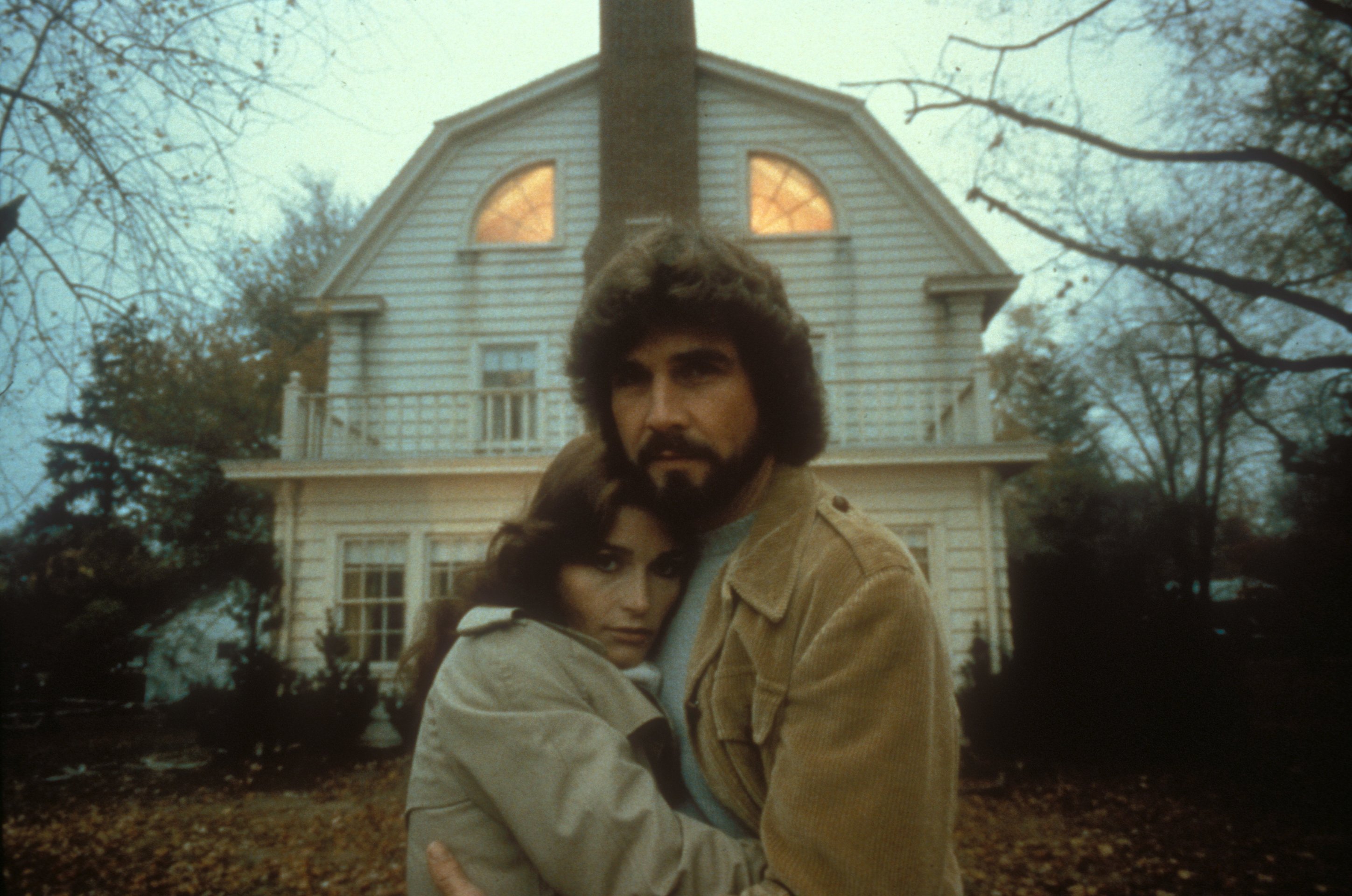 George and Kathy Lutz (James Brolin and Margot Kidder) stand in front of the Amityville house