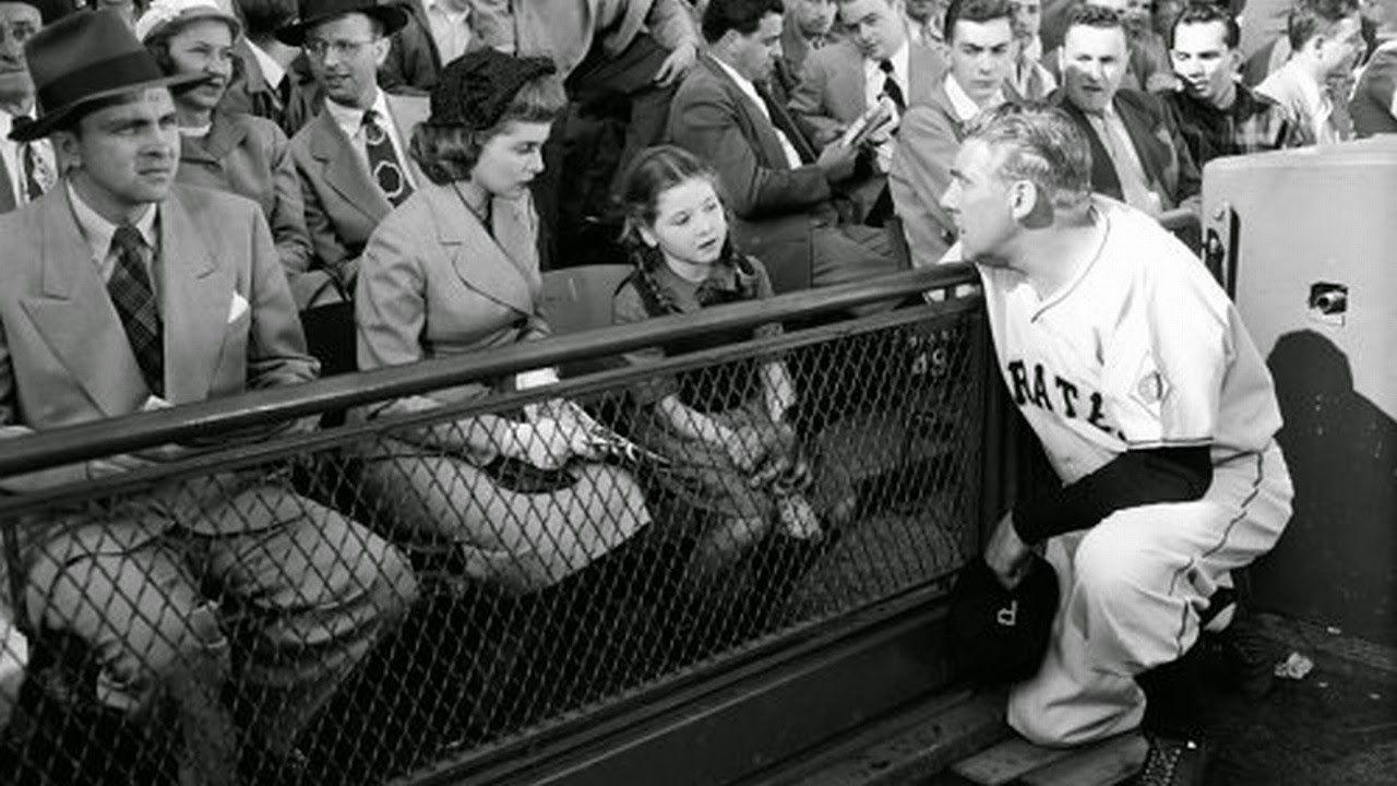 Coach Paul Douglas stops on the sideline to talk to young Donna Corcoran who claims to see angels. With reporter Janet Leigh to her left in Angels in the Outfield (1951)