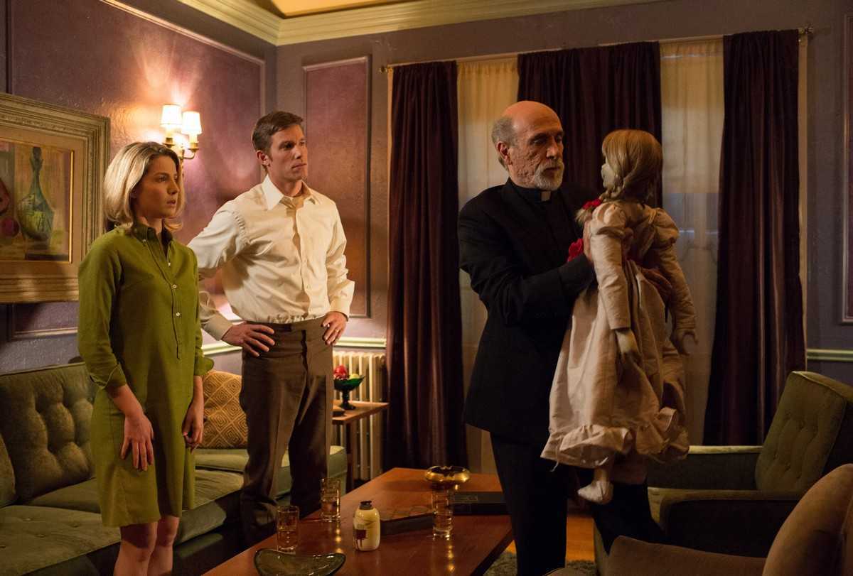 Husband and wife Annabelle Wallis and Ward Horton look on as priest Tony Amendola attempts to exorcise the doll in Annabelle (2004)