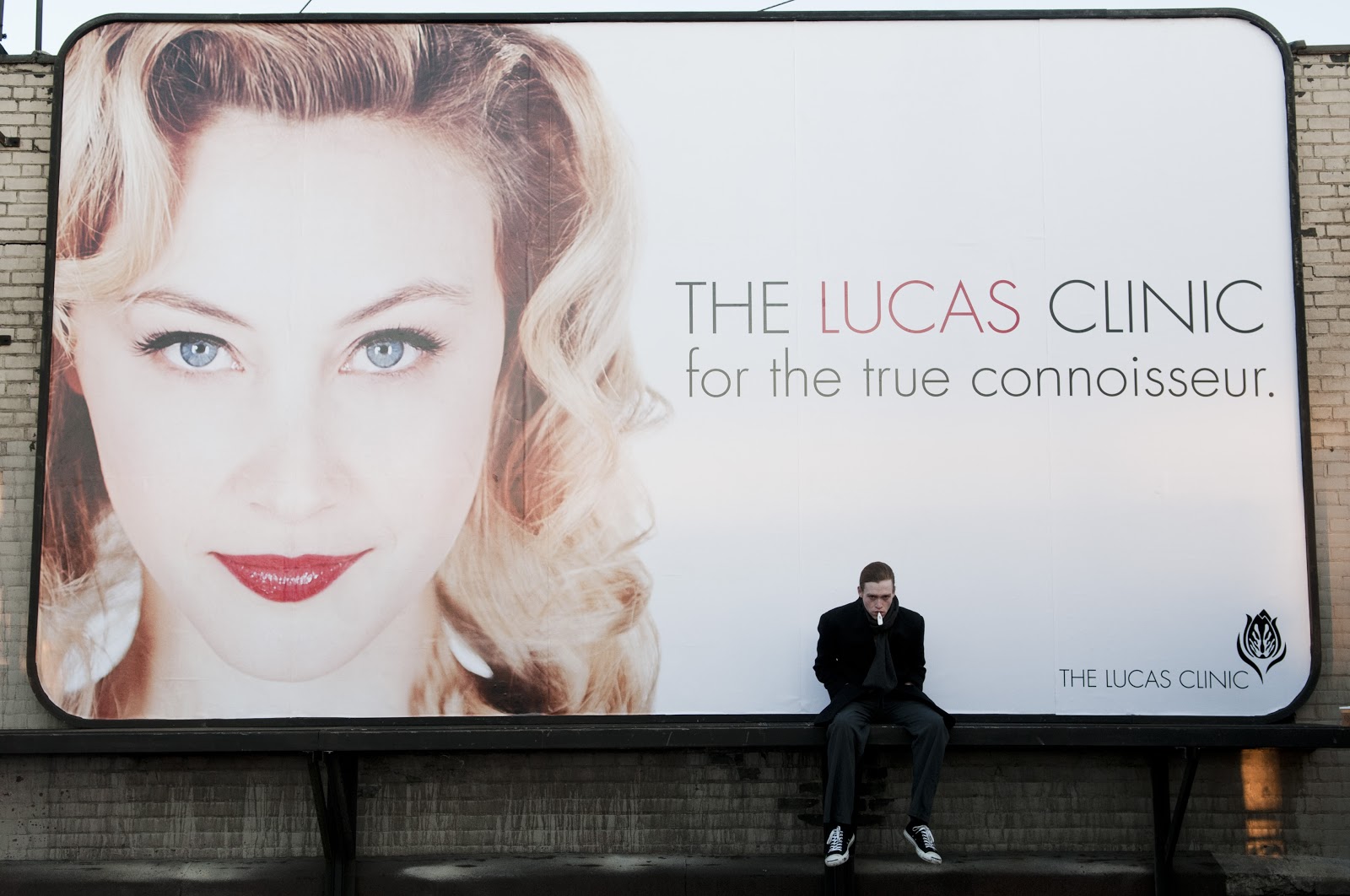 Caleb Landry Jones sits against a poster of Sarah Gadon in Antiviral (2012) - a future that is a satiric escalation o current obsessions with celebrity