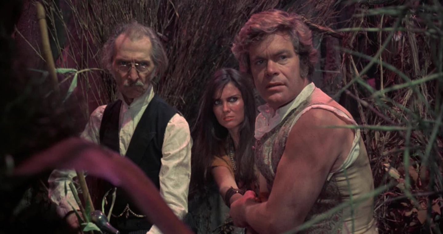 Dr Abner Perry (Peter Cushing), native girl Princess Dia (Caroline Munro) and David Innes (Doug McClure) in At the Earth's Core (1976)