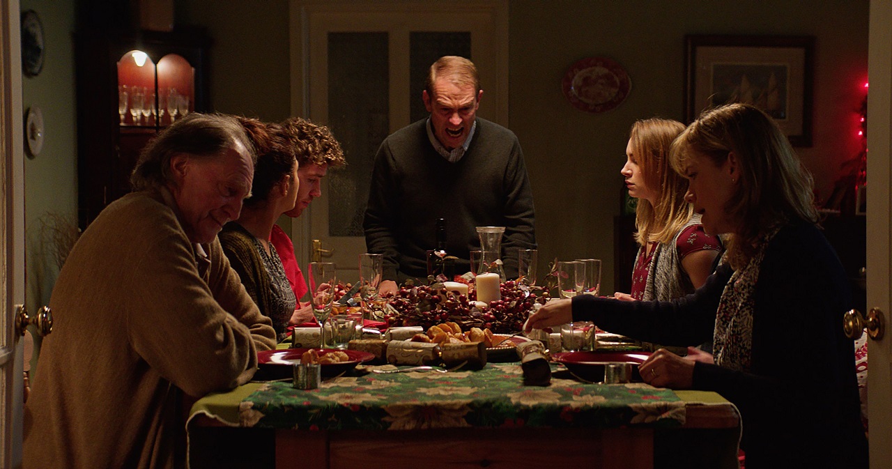 Sitting down to family dinner - (clockwise from left) Grandad David Bradley, the girlfriend Neerja Naik, son Sam Gittins, father Grant Masters, daughter Holly Weston and wife Abigail Cruttenden in Await Further Instructions (2018)