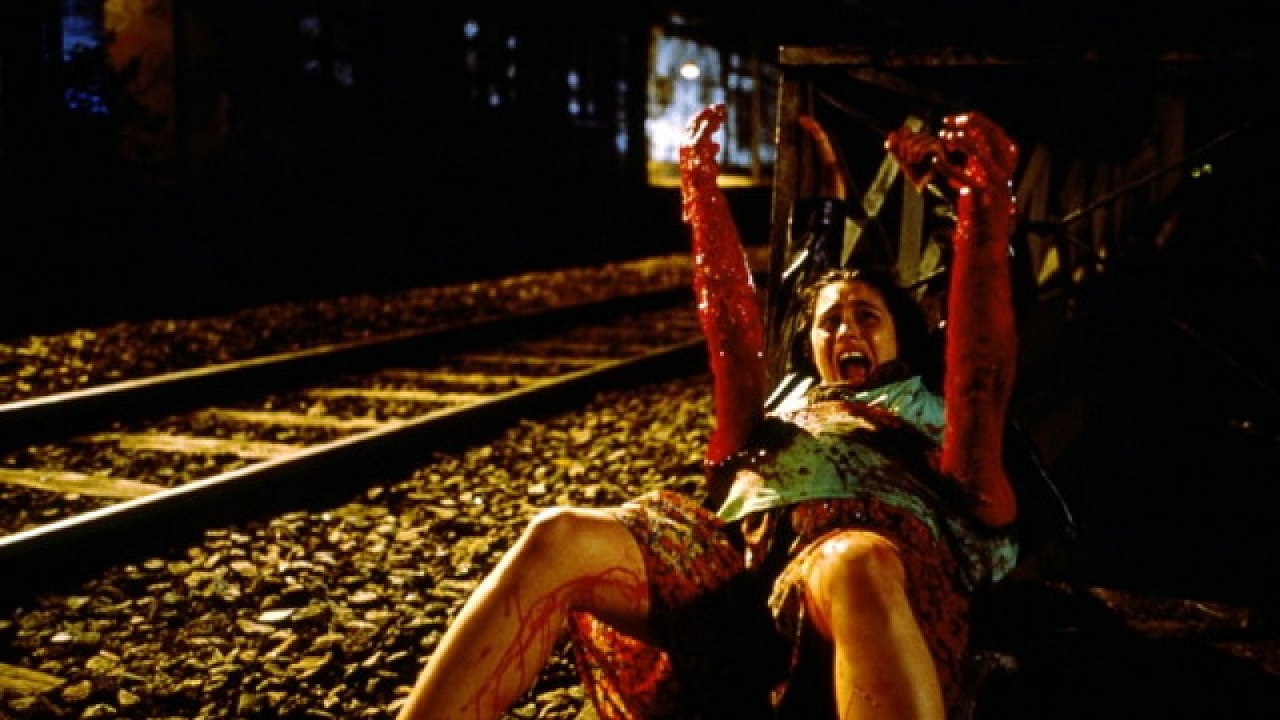 Emmanuelle Escourrou on a railway line as bloody arms burst out of her womb in Baby Blood (1990)
