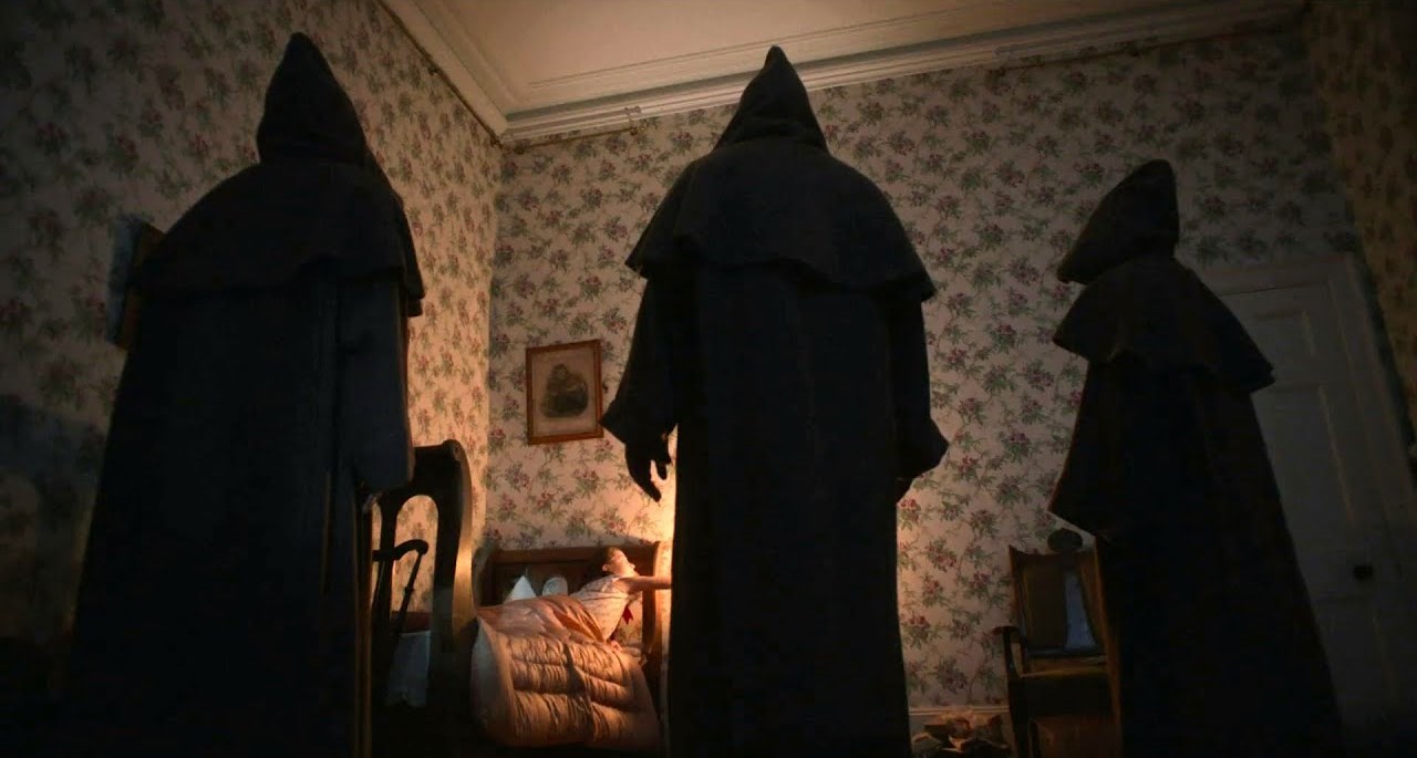 Young Anya McKenna-Bruce surrounded by hooded figures in The Banishing (2020)