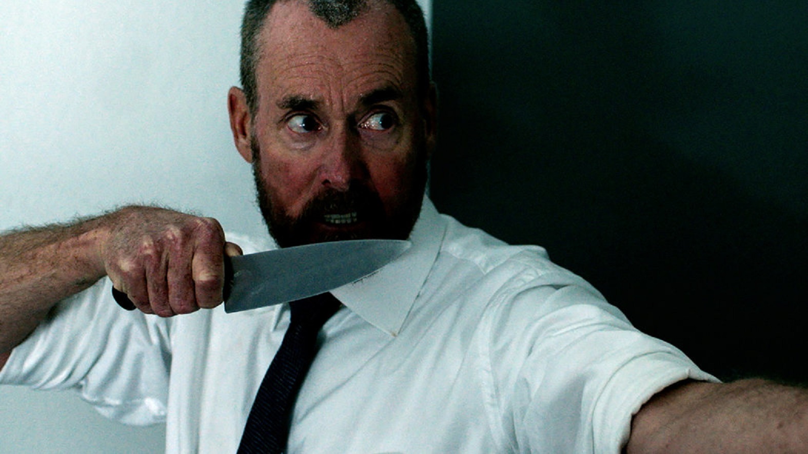 John C. McGinley moves through the office armed with knife in The Belko Experiment (2016)