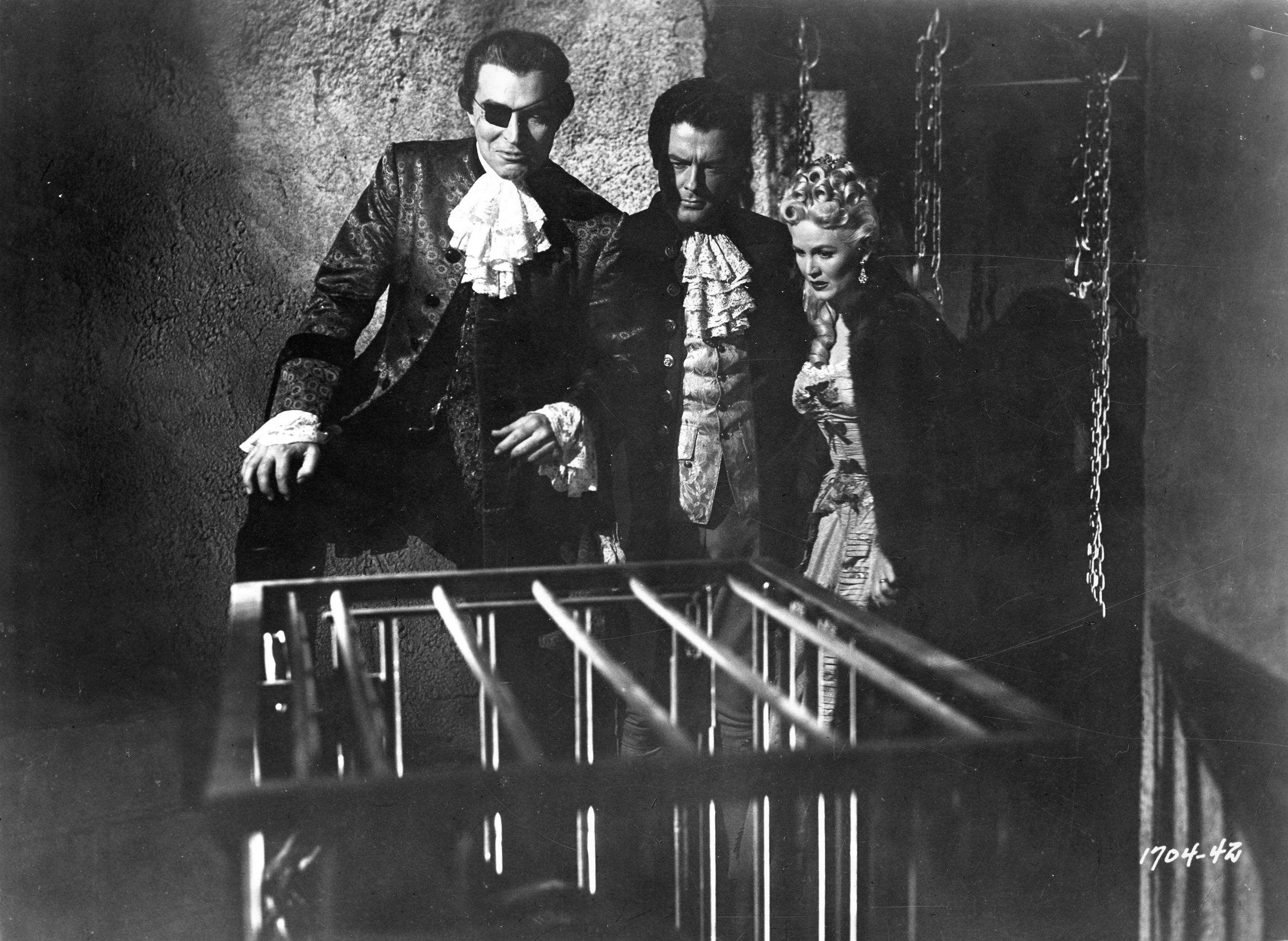 (l to r) Count Von Bruno (Stephen McNally) introduces Richard Greene and Paula Corday to his panther cage in The Black Castle (1952)