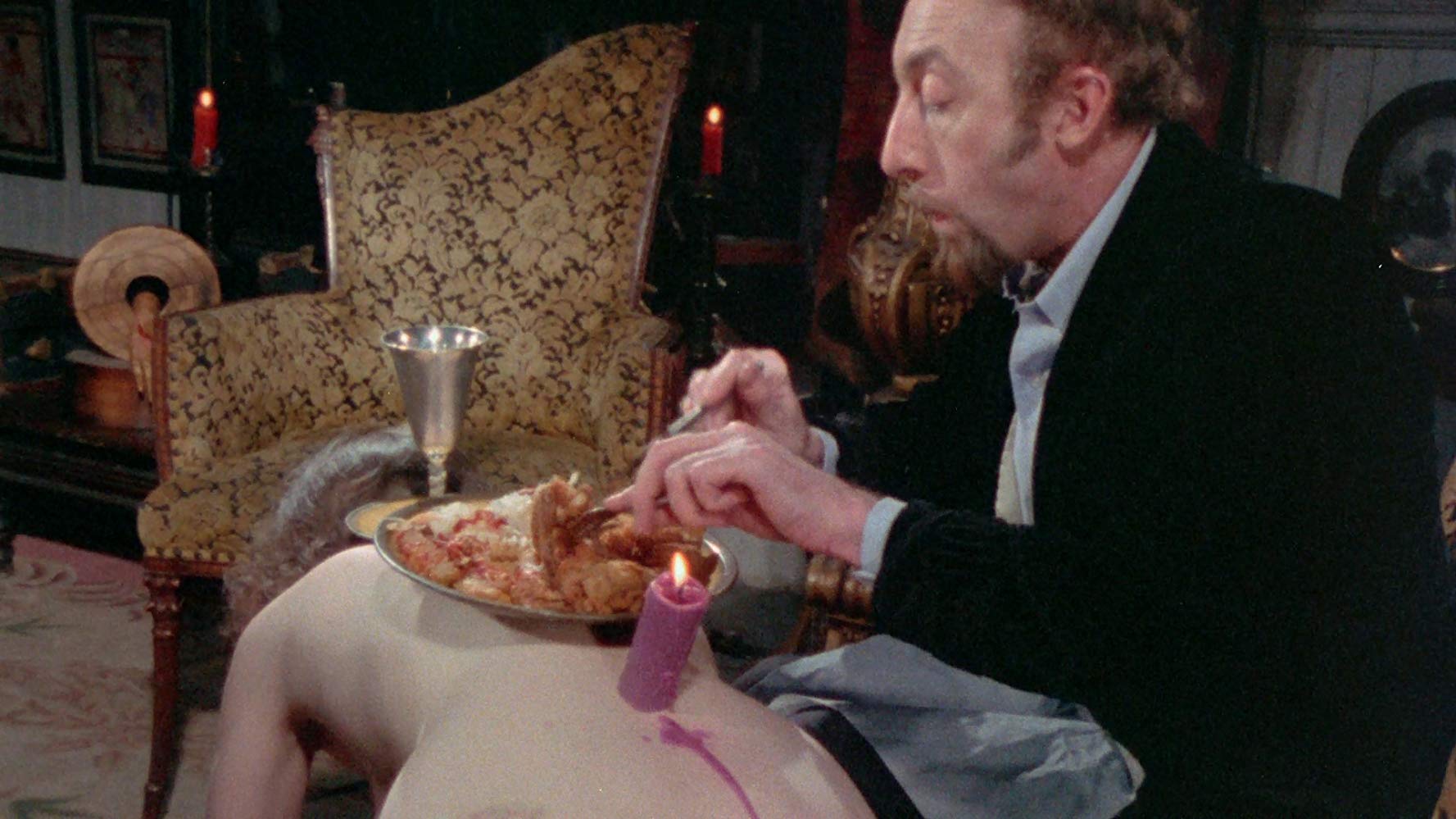 Sardu (Seamus O’Brien) eats his dinner off a victim's body in Blood Sucking Freaks (1976)