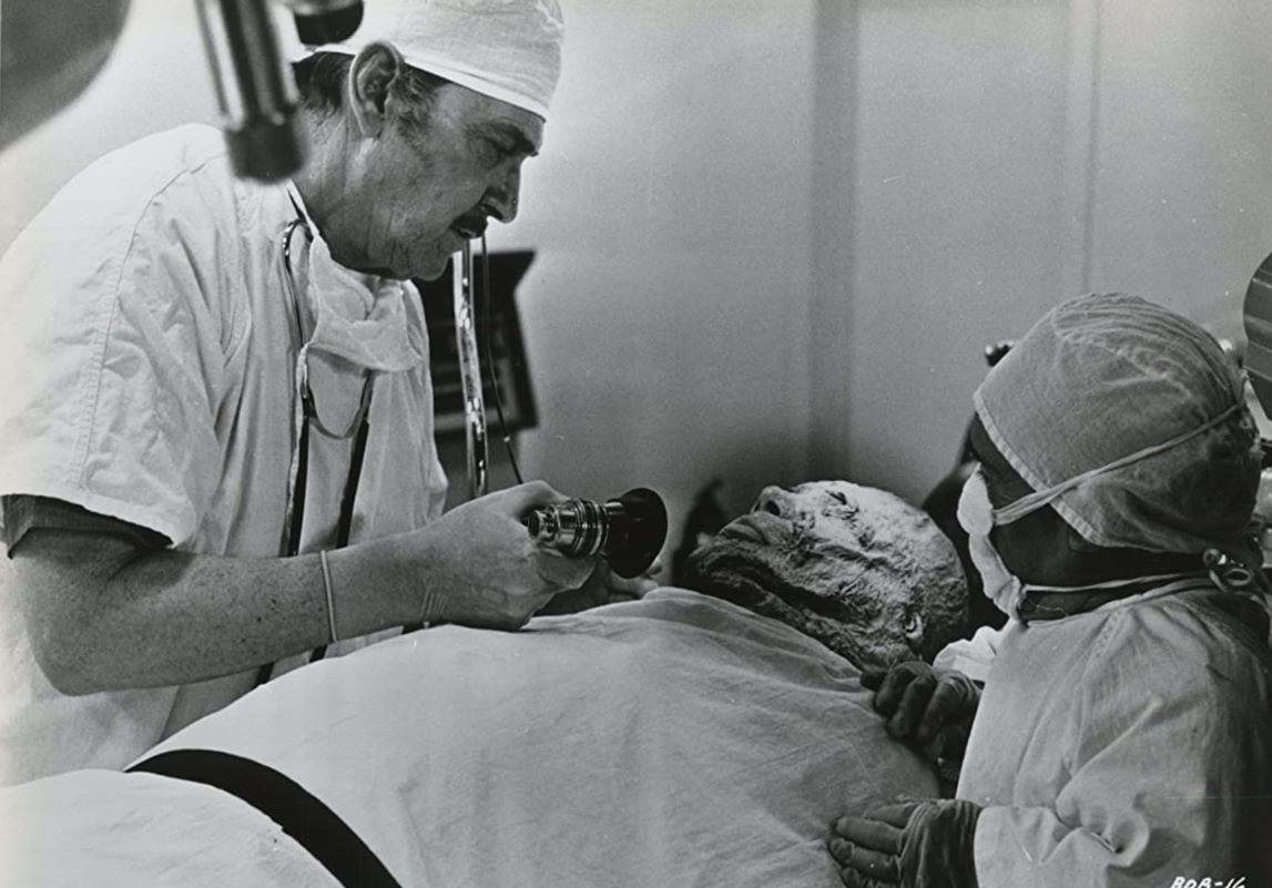 Dr Lloyd Trenton (Kent Taylor) aided by dwarf lab assistant Dorro (Angelo Rossitto) prepares to remove the brain of Abdul Amir in Brain of Blood (1971)