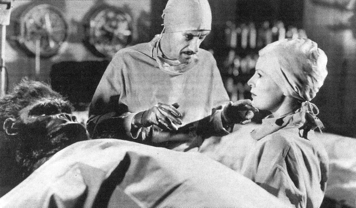 Mad scientist John Carradine about to deal with objections from nurse Fay Helm as he prepares to operate on the gorilla in Captive Wild Woman (1943)