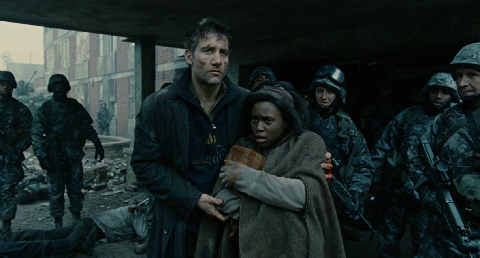 Clive Owen guides pregnant Claire-Hope Ashitey through the refugee camp in Children of Men (2006)