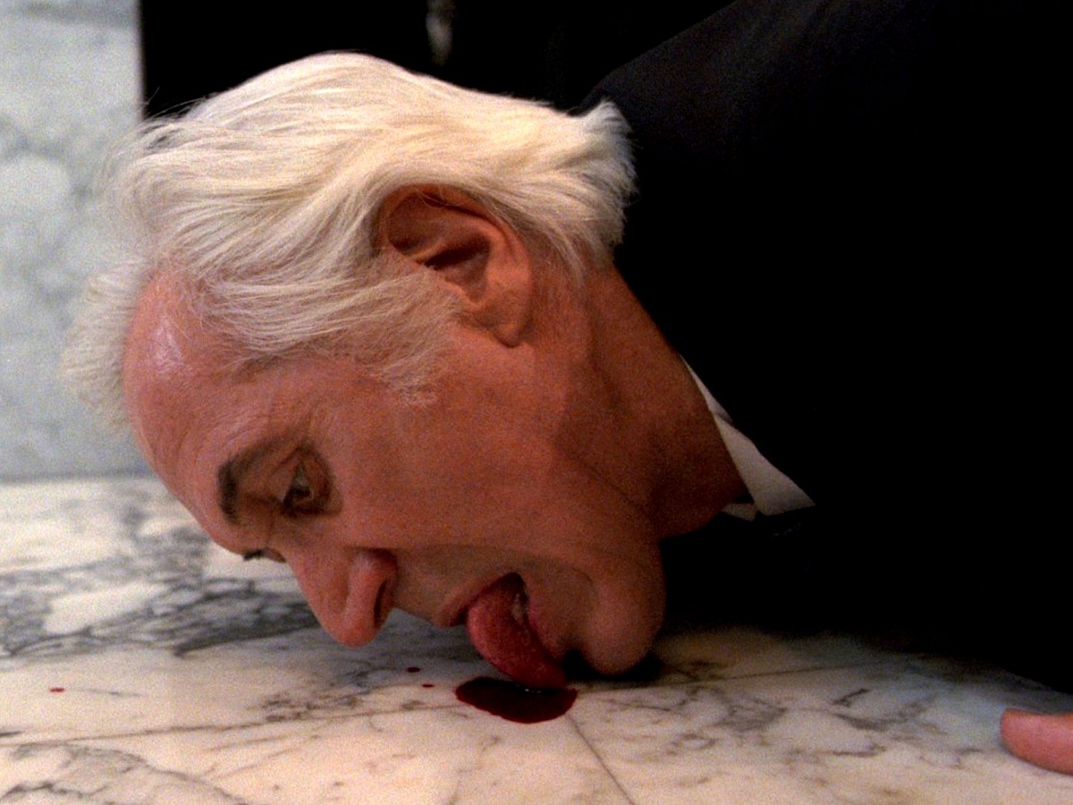 Federico Luppi gets down to drink the blood on a bathroom floor in Cronos (1993)