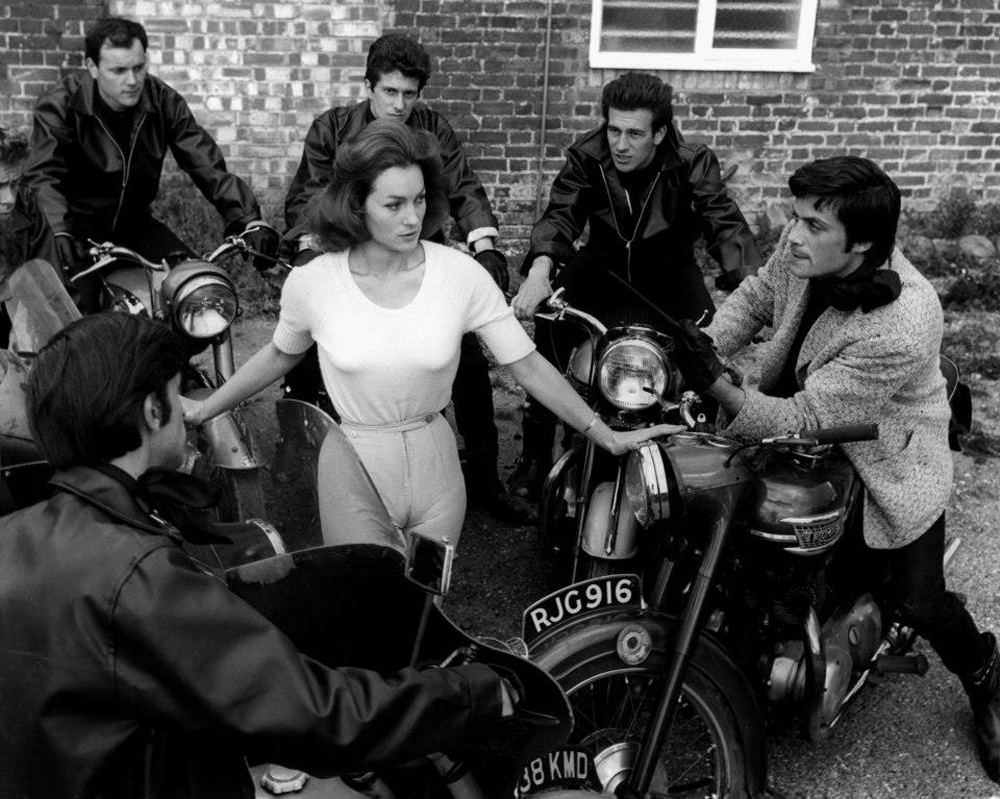 Shirley Ann Field surrounded by teddy boys with the leader King (Oliver Reed) on the right in The Damned (1963)