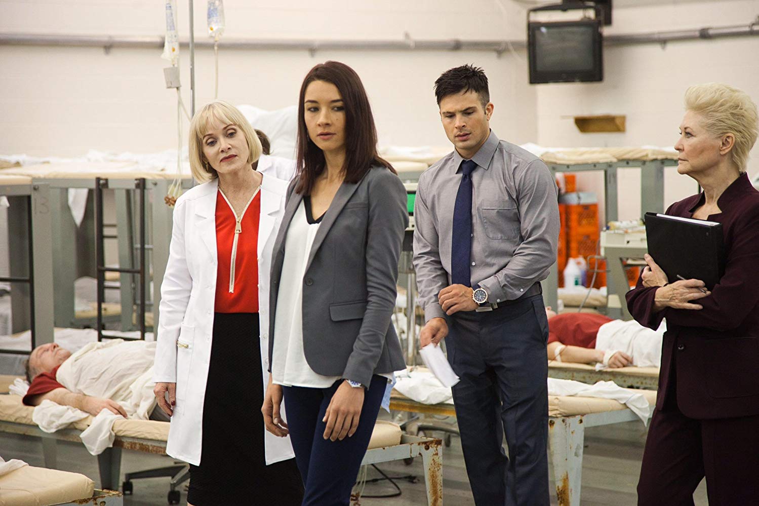 FBI agents Cornet Palm and Cody Longo are introduced to the virtual reality system by scientists Barbara Crampton (l) and Dee Wallace (r) in Death House (2017)