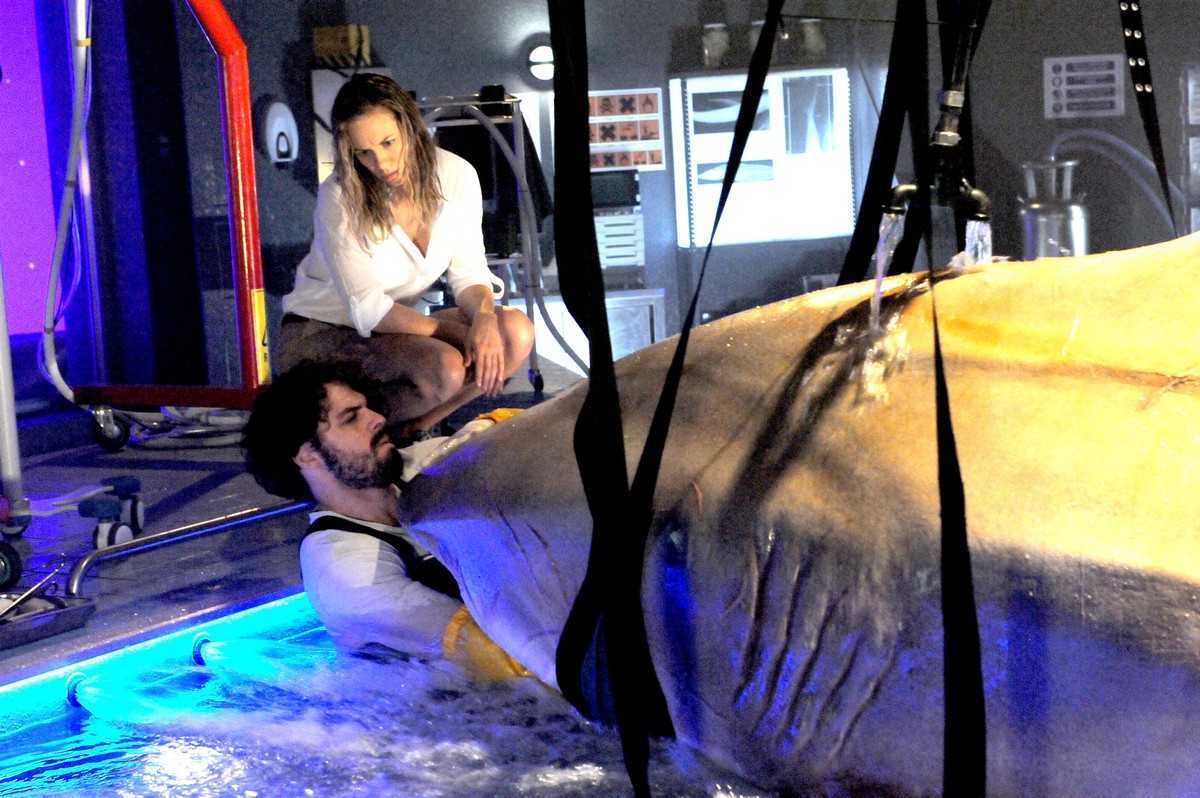 Danielle Savre looks on while Nathan Lynn places his arm in a shark's mouth in Deep Blue Sea 2 (2018)