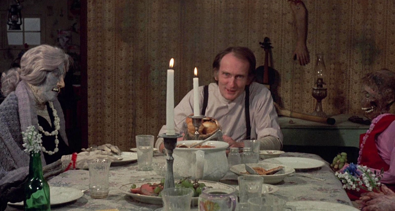 Roberts Blossom having dinner at a table of mummified corpses in Deranged (1974)