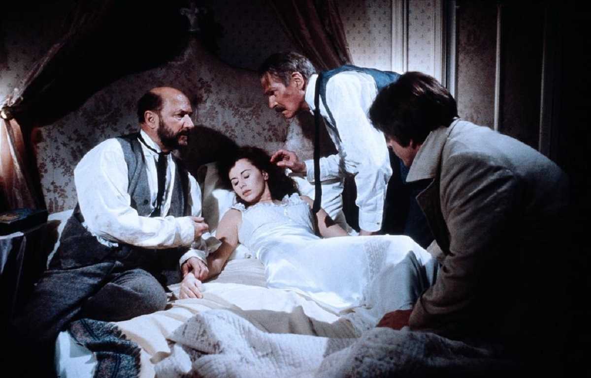 A bedridden Lucy Seward (Kate Neliigan) is tended by (l to r) Dr Seward (Donald Pleasence), Professor Van Helsing (Laurence Olivier) and Jonathan Harker (Trevor Eve) in Dracula (1979)