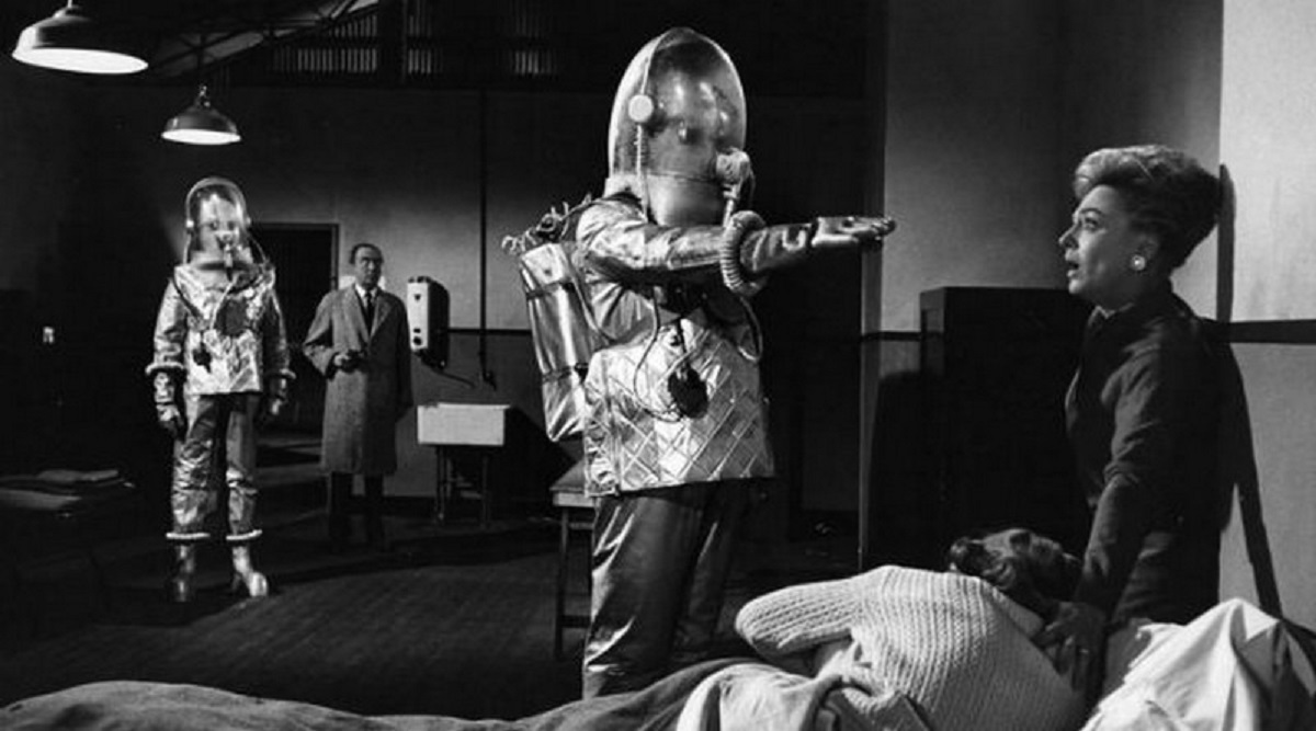 The invading alien robots threaten Vanda Godsell with a mind-controlled Dennis Price in the background in The Earth Dies Screaming (1964)