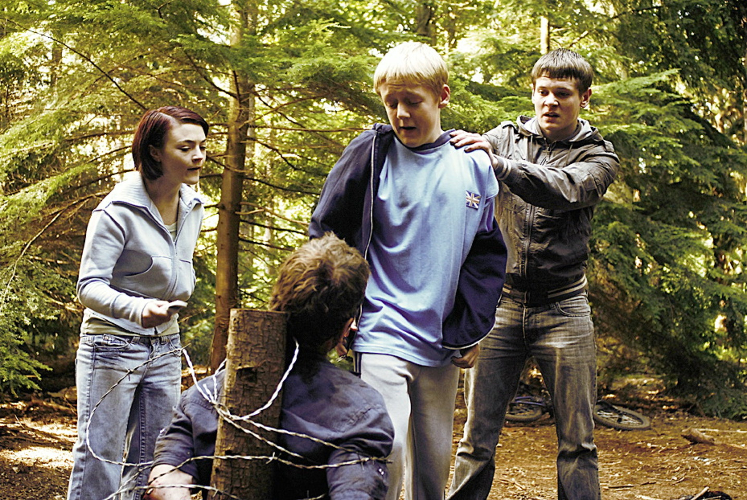 A bound Michael Fassbender is tortured by children - (l to r) Finn Atkins, Thomas Turgoose and Jack O’Connell) in Eden Lake (2008)