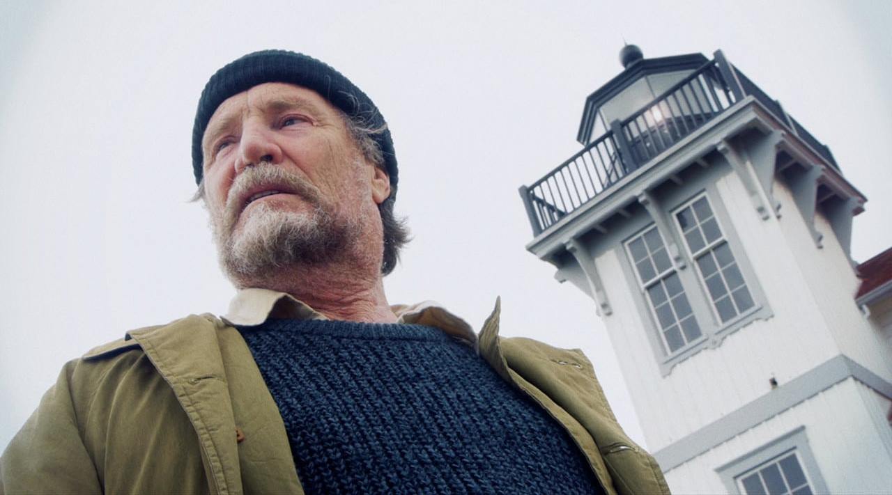 Vernon Wells as the lighthouse keeper alongside the lighthouse he tends in Edgar Allan Poe's Lighthouse Keeper (2016)