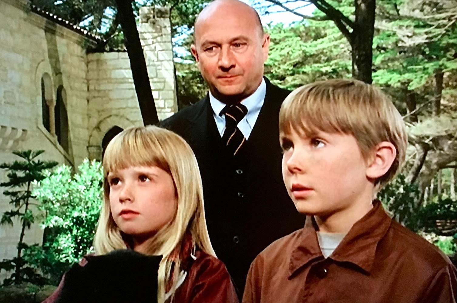 Psychically gitted alien children Tia (Kim Richards) and Tony (Ike Eisenmann) with pursuing henchman Lucas Derenian (Donald Pleasence) in the background in Escape to Witch Mountain (1975)