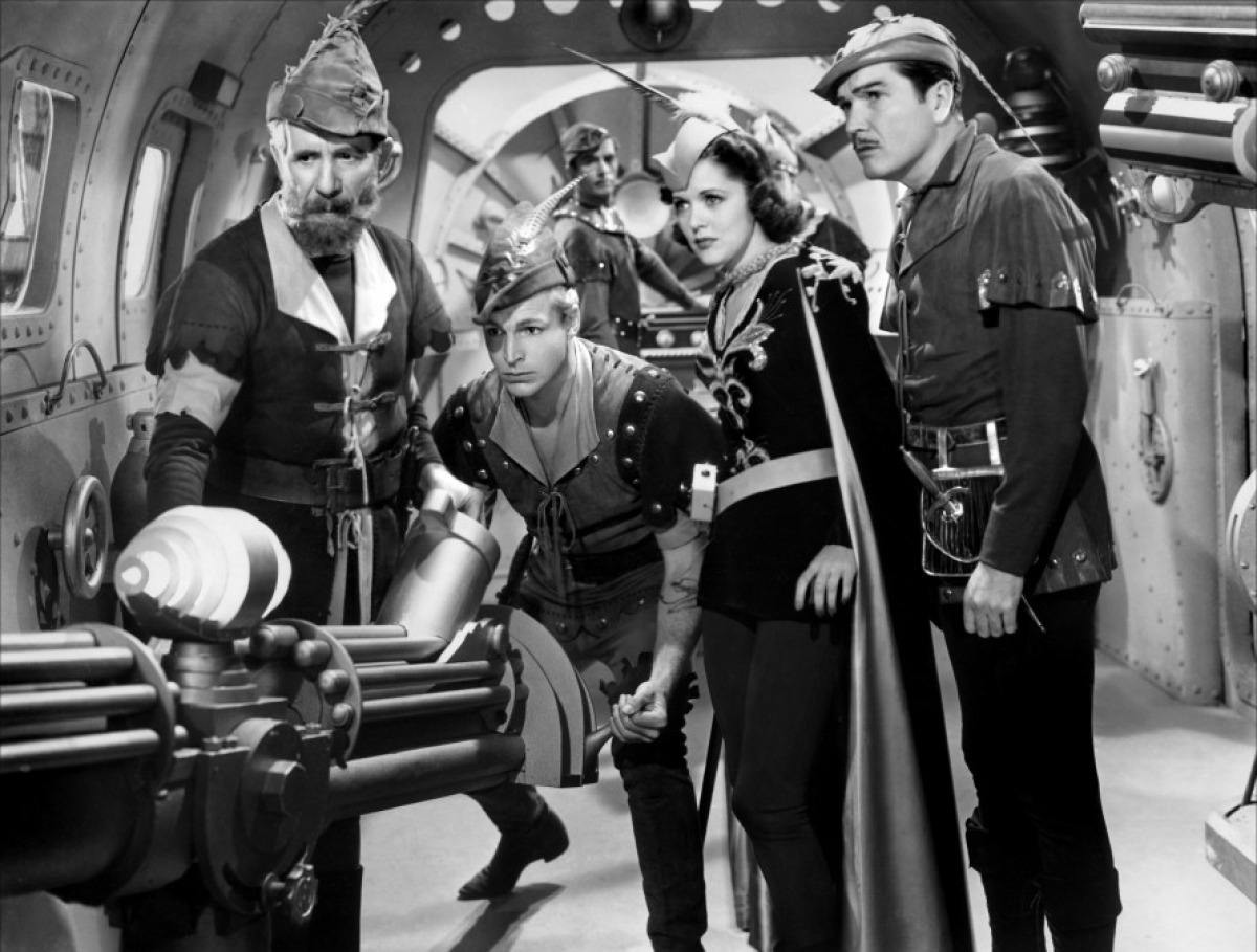 (l to r) Dr Zarkov (Frank Shannon), Flash Gordon (Larry ‘Buster’ Crabbe), Dale Arden (Carol Hughes) and Prince Barin (Roland Drew) in Flash Gordon Conquers the Universe (1940)