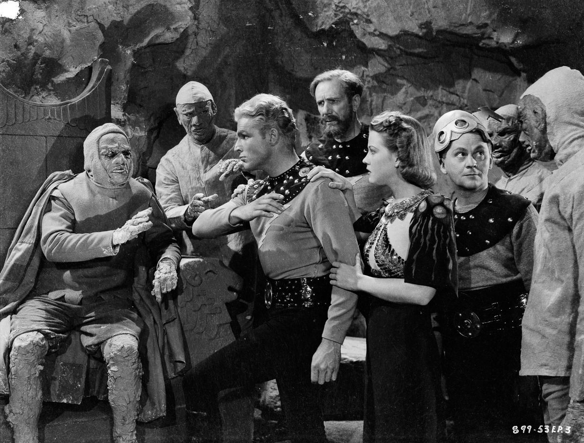 (l to r) Flash Gordon (Larry ‘Buster’ Crabbe), Dr Zarkov (Frank Shannon), Dale Arden (Jean Rogers) and comic relief Happy Hapgood (Donald Kerr) among the Clay People in Flash Gordon's Trip to Mars (1938)