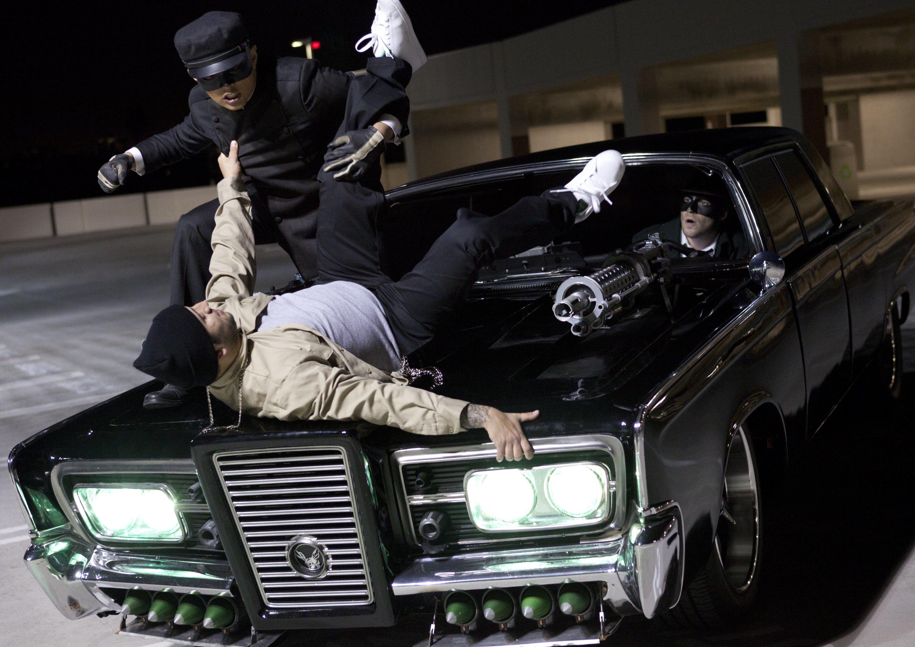 Kato (Jay Chou) stops a hoodlum atop the hood of Black Beauty with The Green Hornet (Seth Rogen) behind the wheel in The Green Hornet (2011)