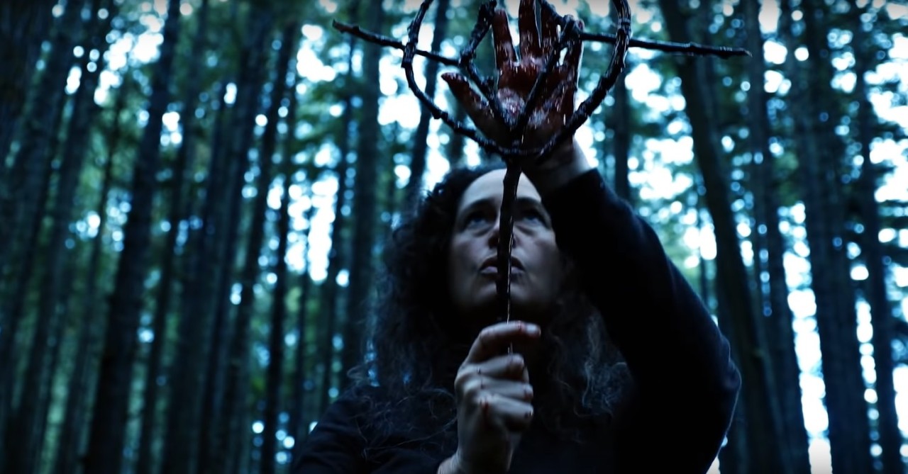 Toby Poser prepares a ritual in the woods in Hellbender (2021)