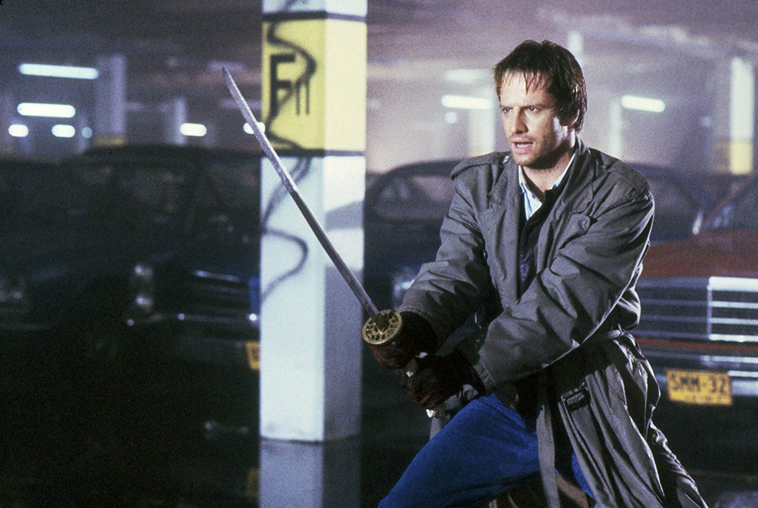 Connor McLeod (Christopher Lambert) enters a duel in a carpark building in Highlander (1986)