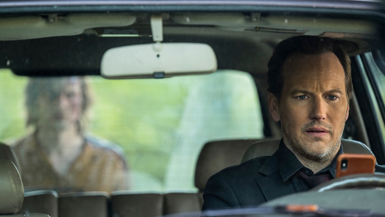 Patrick Wilson on his phone as a figure approaches his vehiclein Insidious: The Red Door (2023)