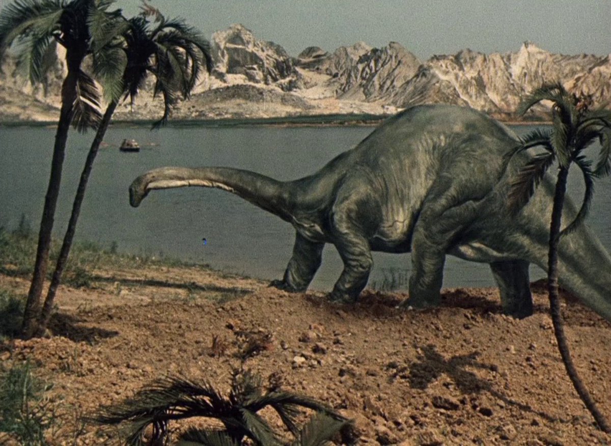 The boys pass a brontosaurus on their boat journey through prehistory in Journey to the Beginning of Time (1955)