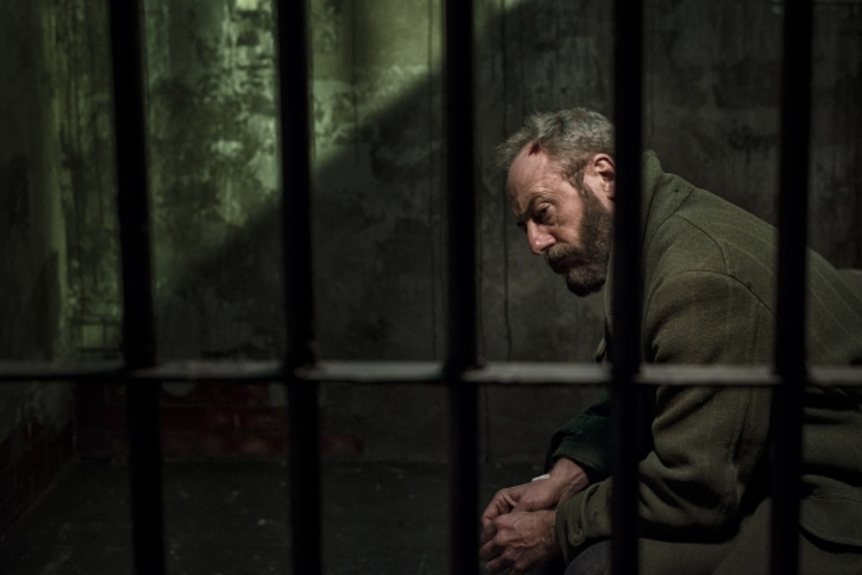 Liam Cunningham, a mysterious stranger manipulating the secrets of a town from within a jail cell in Let Us Prey (2014)