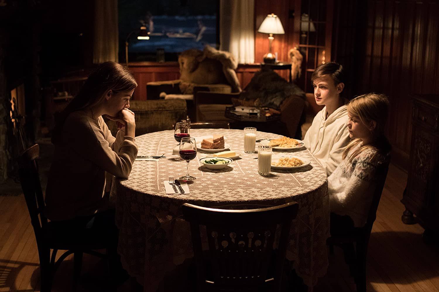 Grace (Riley Keough) sits down to dine with the children (Jaeden Martell and Lia McHugh) in The Lodge (2019)