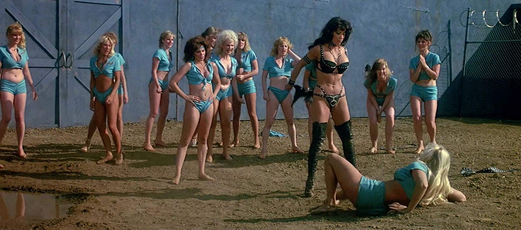 An entirely gratuitous women's prison catight scene with Angelique Pettyjohn (in black leather) standing over Angela Aames in The Lost Empire (1983)