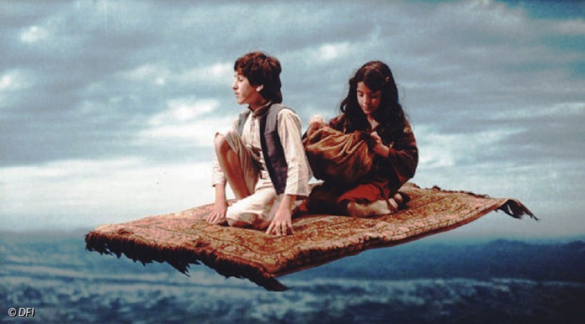 Hadja (David Bertelsen) aboard the flying carpet with Emerald (Zuhal Ozdemir) in The Magic Carpet (1985)