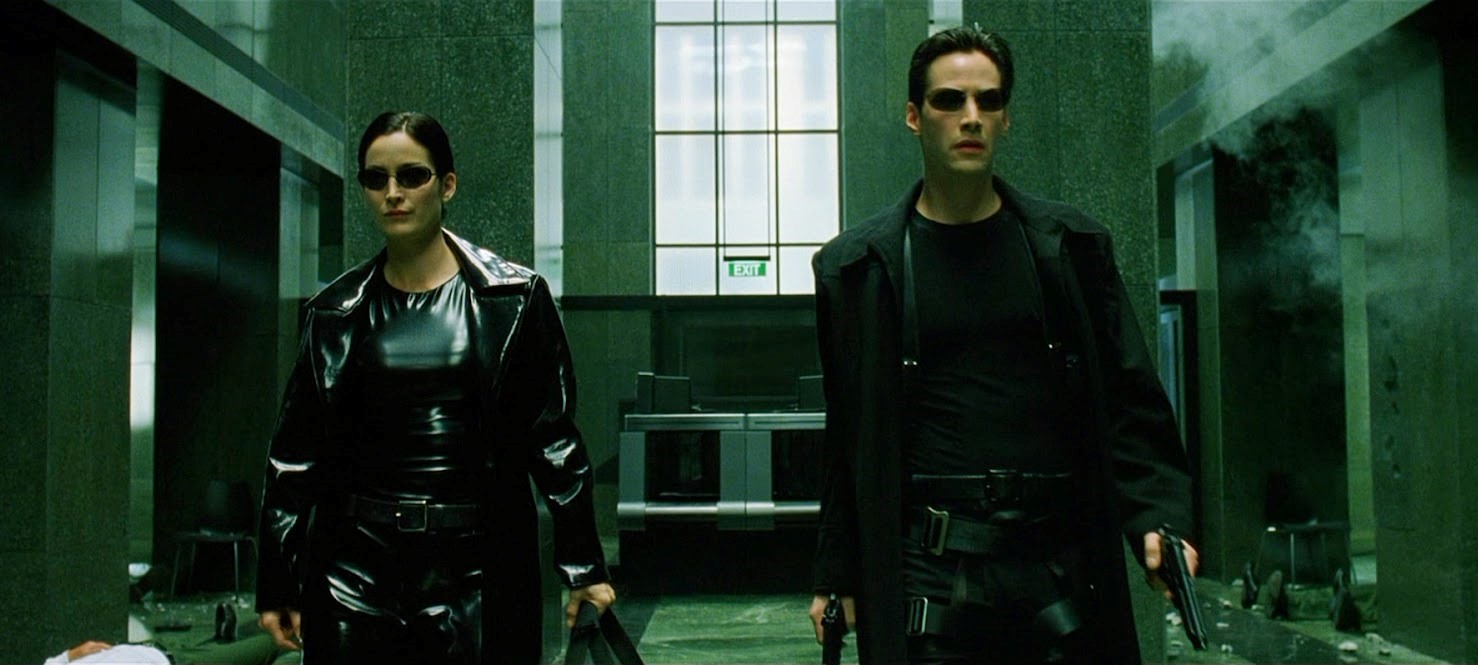 Trinity (Carrie-Anne Moss) and Neo (Keanu Reeves) - the sublime cool of heading into action in black leathers, PVC and shades in The Matrix (1999)