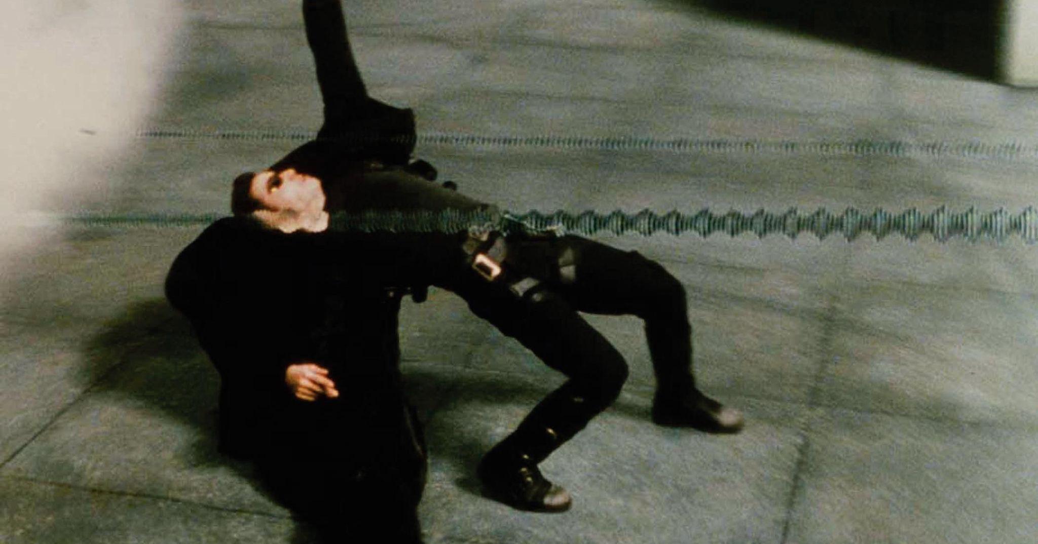 Keanu Reeves ducks bullets in the Bullet time sequence in The Matrix (1999)