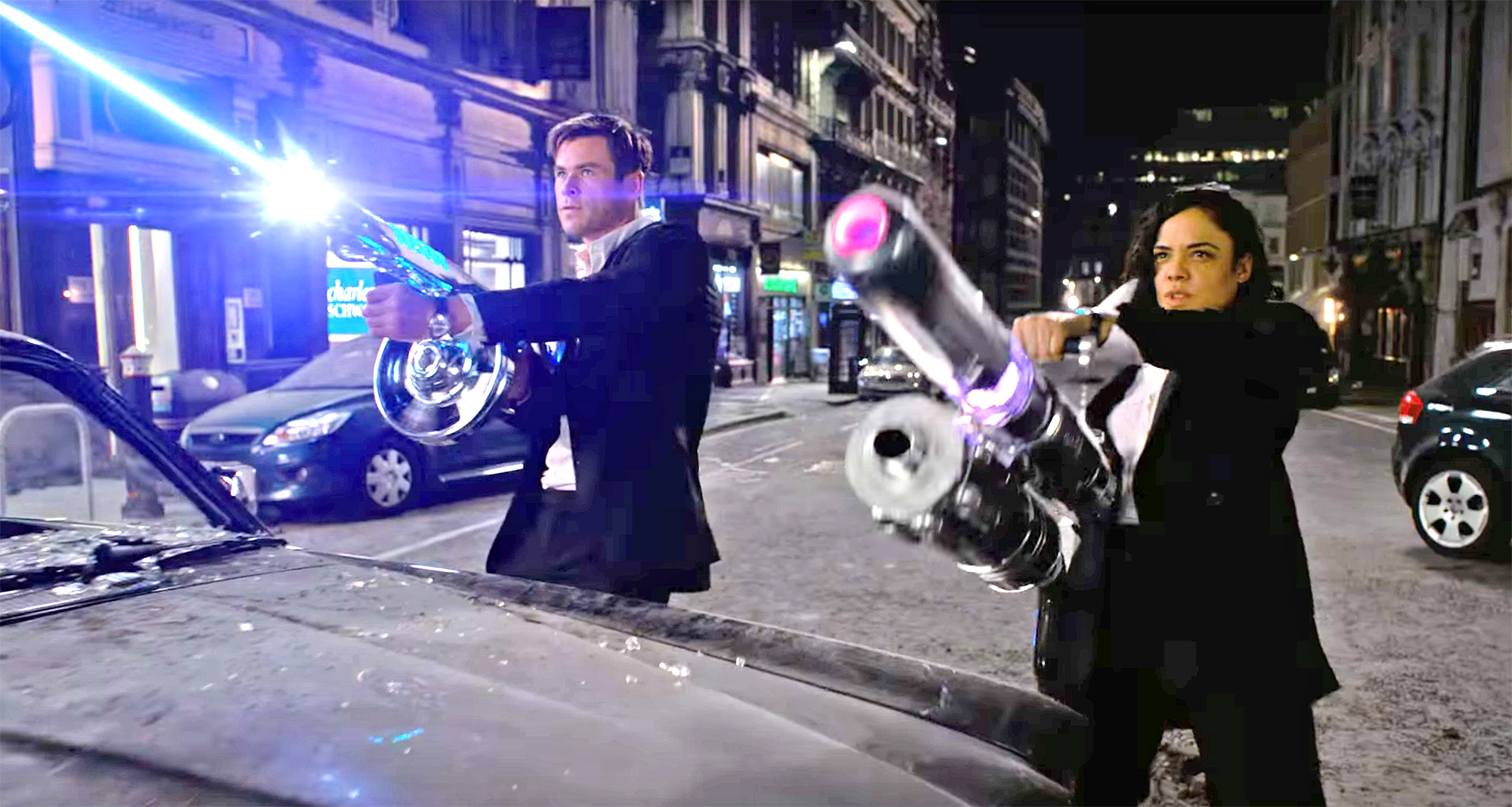 Agents M (Tessa Thompson) and H (Chris Hemsworth) wield weaponry against alien assassins in London in Men in Black: International (2019)