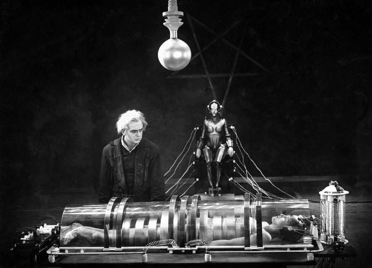 The scientist Rotwang (Rudolf Klein-Rogge) surveys the imprisoned Maria (Brigitte Helm) as he prepares to bring the robot to life in Metropolis (1927)