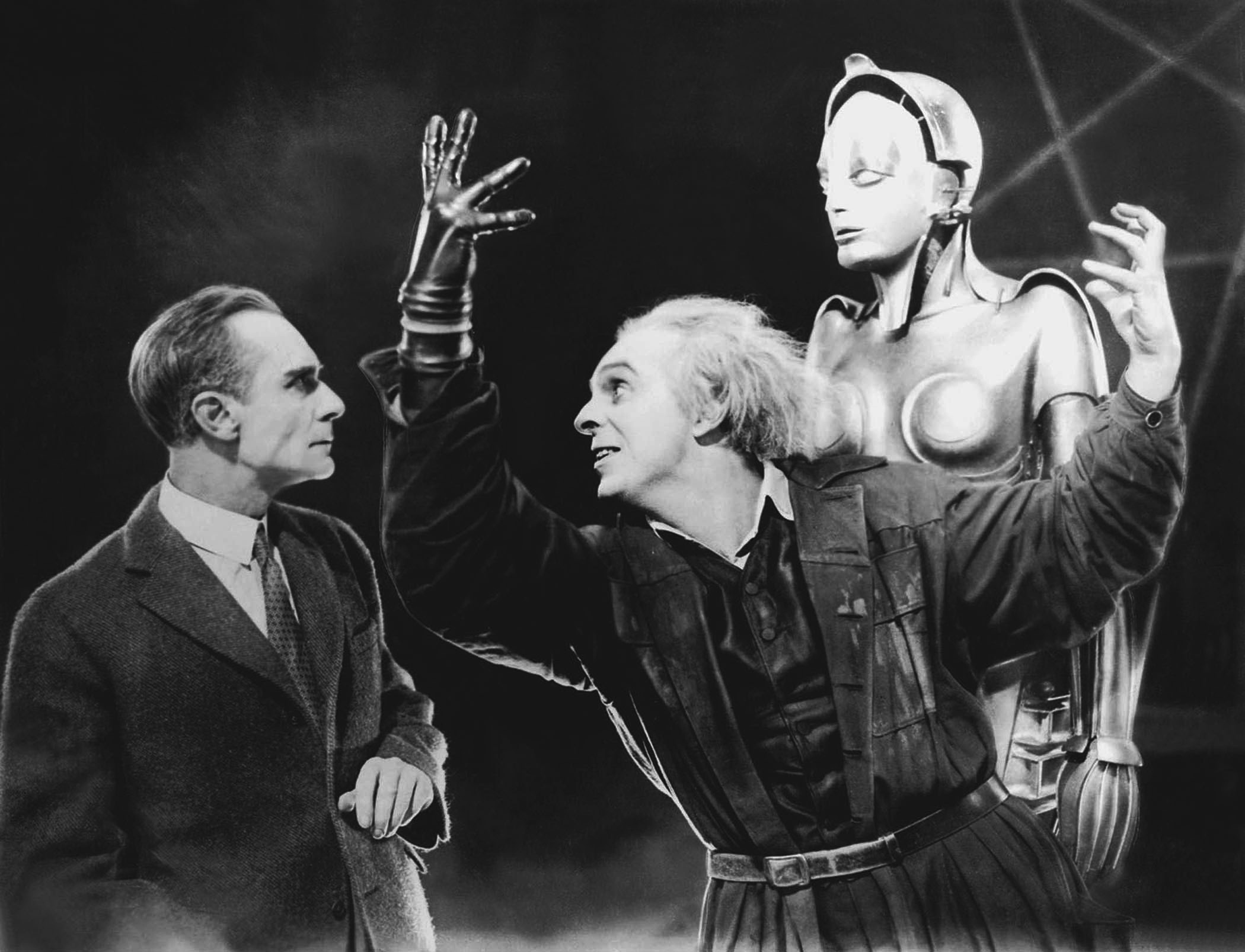 Rotwang (Rudolf Klein-Rogge) remonstrates to Joh Fredersen (Alfred Abel) while the robot Maria (Brigitte Helm) looks on in Metropolis (1927)