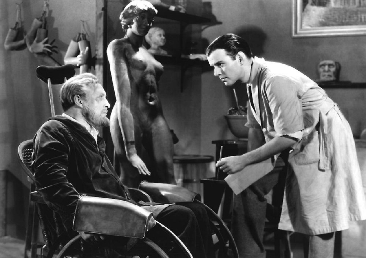 (l to r) The wheelchair-ridden waxworks curator Igor (Lionel Atwill) and his assistant Allen Vincent in Mystery of the Wax Museum (1933)