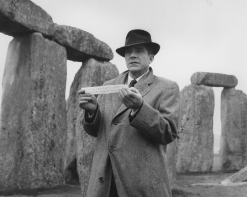 Rationalist hero John Holden (Dana Andrews) receives the rune with Stonehenge in the background in Night of the Demon (1957)