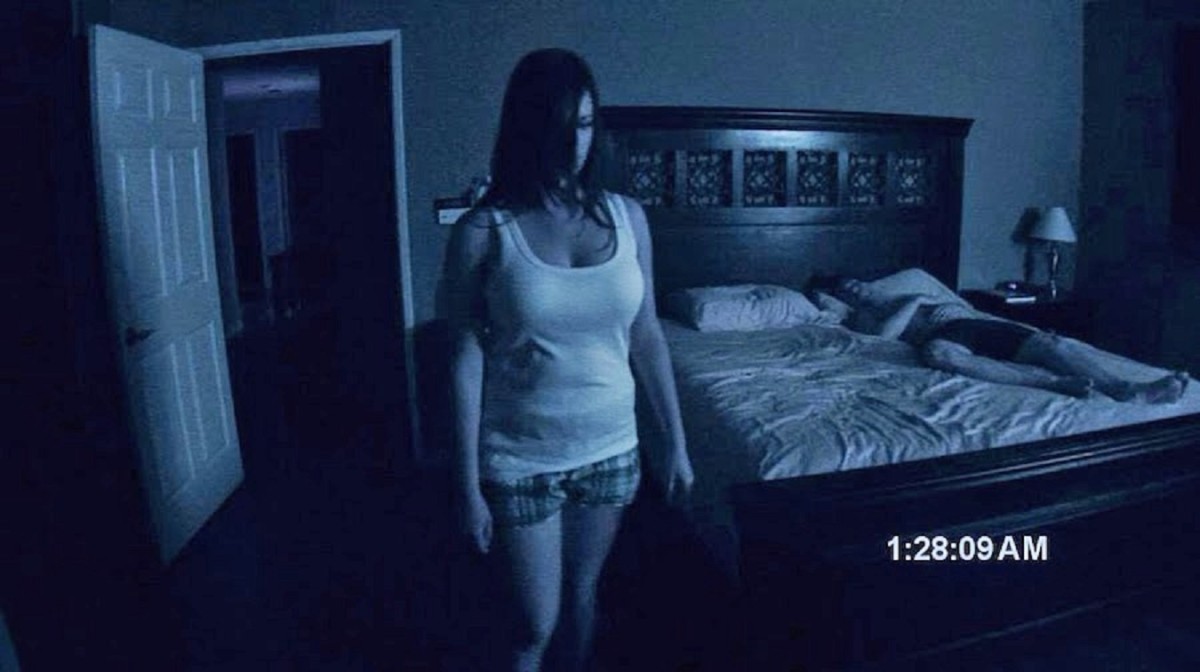 A possessed Katie Featherston stands while Micah Sloat sleeps in Paranormal Activity (2007)
