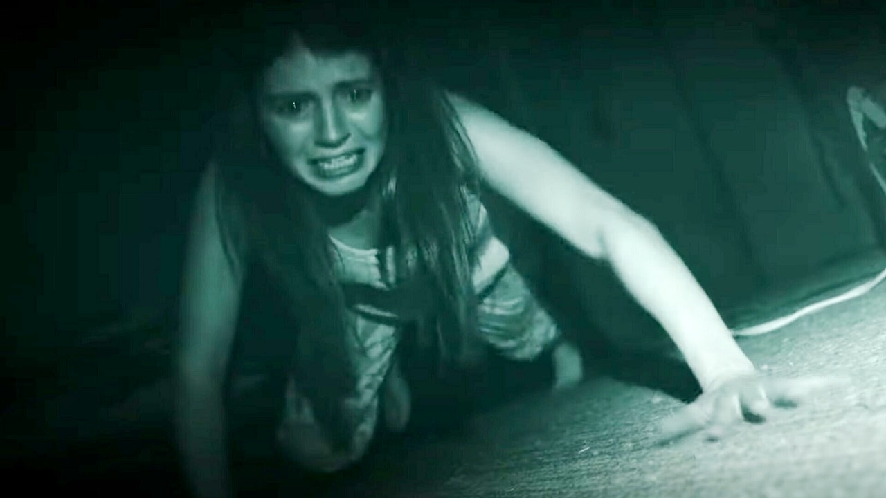 Emily Bader hides under the bed on infra-red camera in Paranormal Activity: Next of Kin (2021)