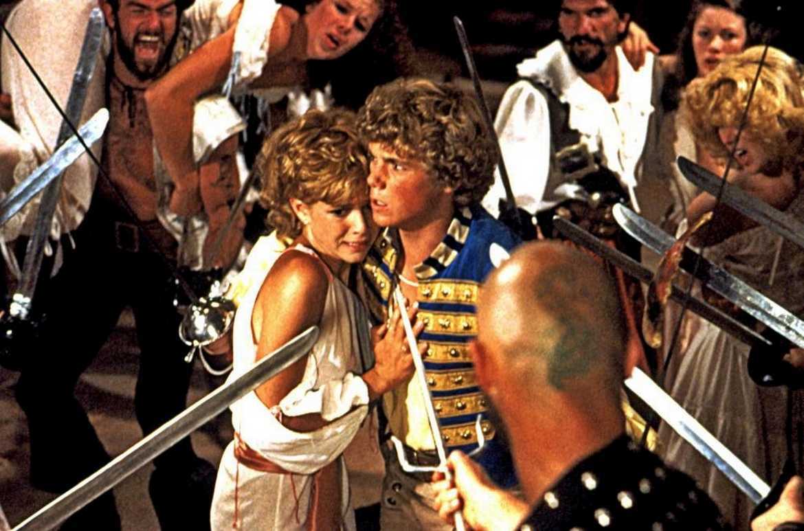 Kristy McNichol and Christopher Atkins surrounded by pirates in The Pirate Movie (1982)