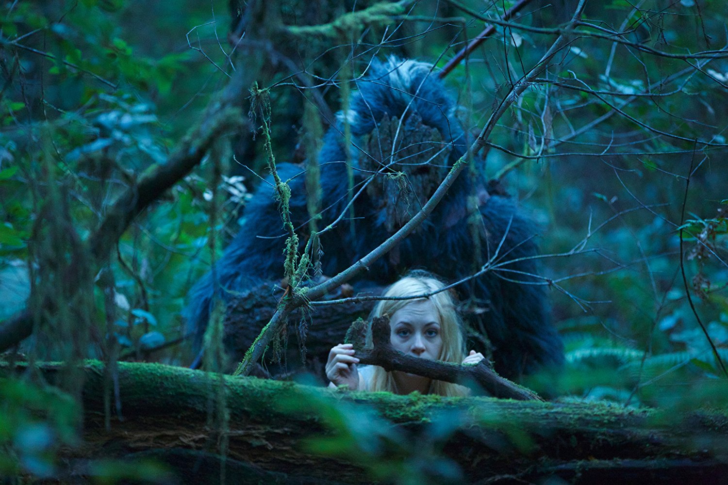 Casey Gagliardi hides in the woods as Bigfoot lurks unseen behind her in Primal Rage (2018)