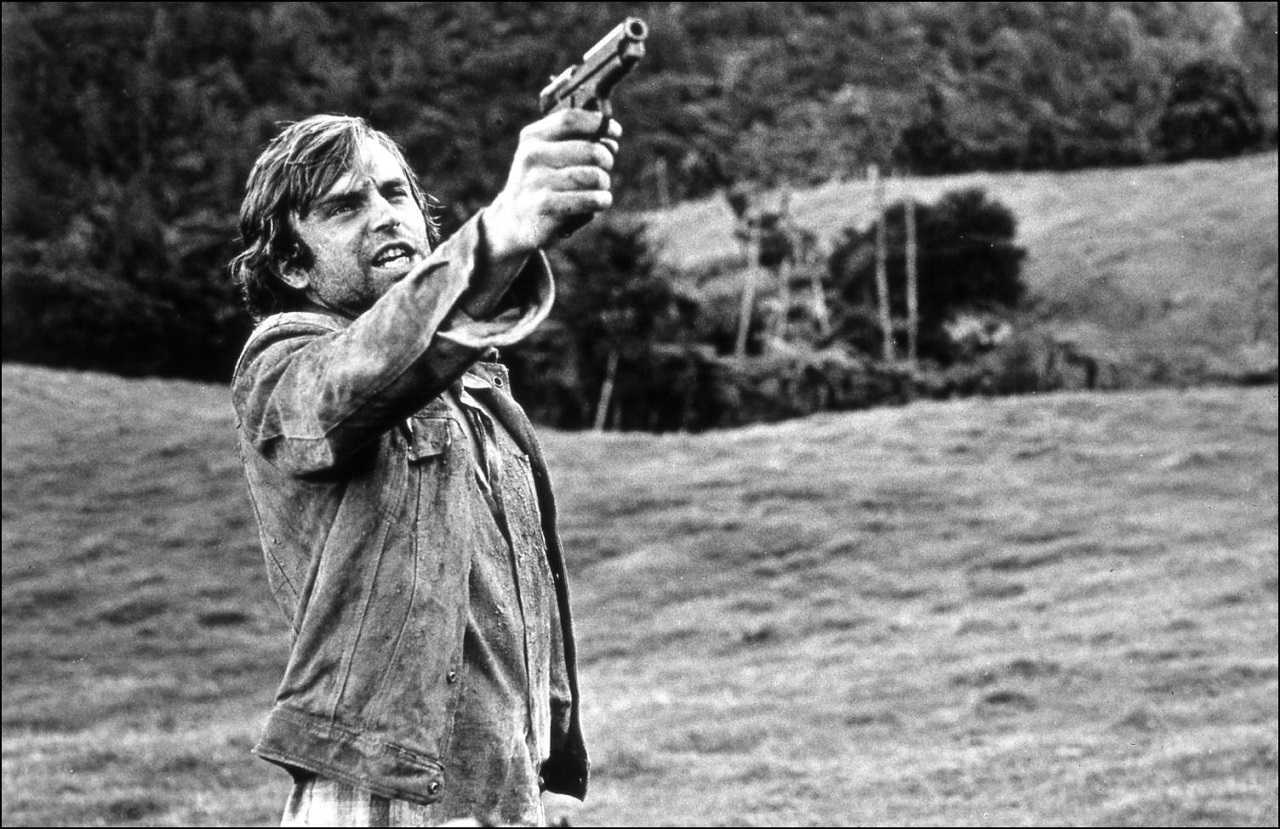 Smith (Sam Neill) shoots back at the pursuing Specials in Sleeping Dogs (1977)