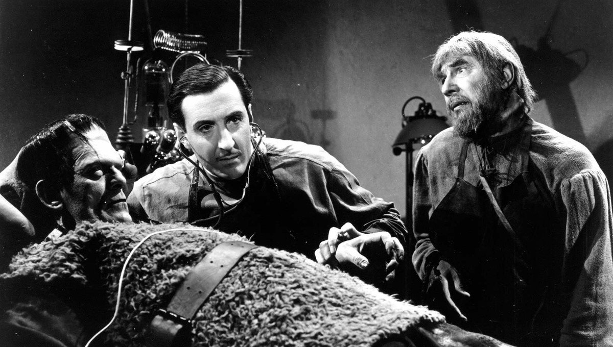 Frankenstein's son (Basil Rathbone) (c) examines the body of the monster (Boris Karloff) (front) while the blacksmith Ygor (Bela Lugosi) (r) looks on in Son of Frankenstein (1939)